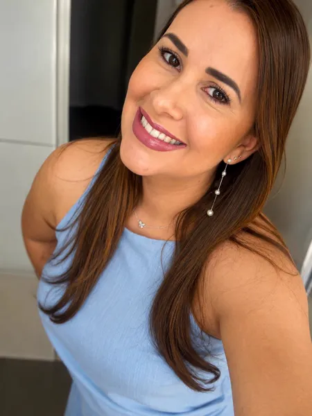 Lidiane Araújo sorrindo, usando brinco de pérolas e colar delicado